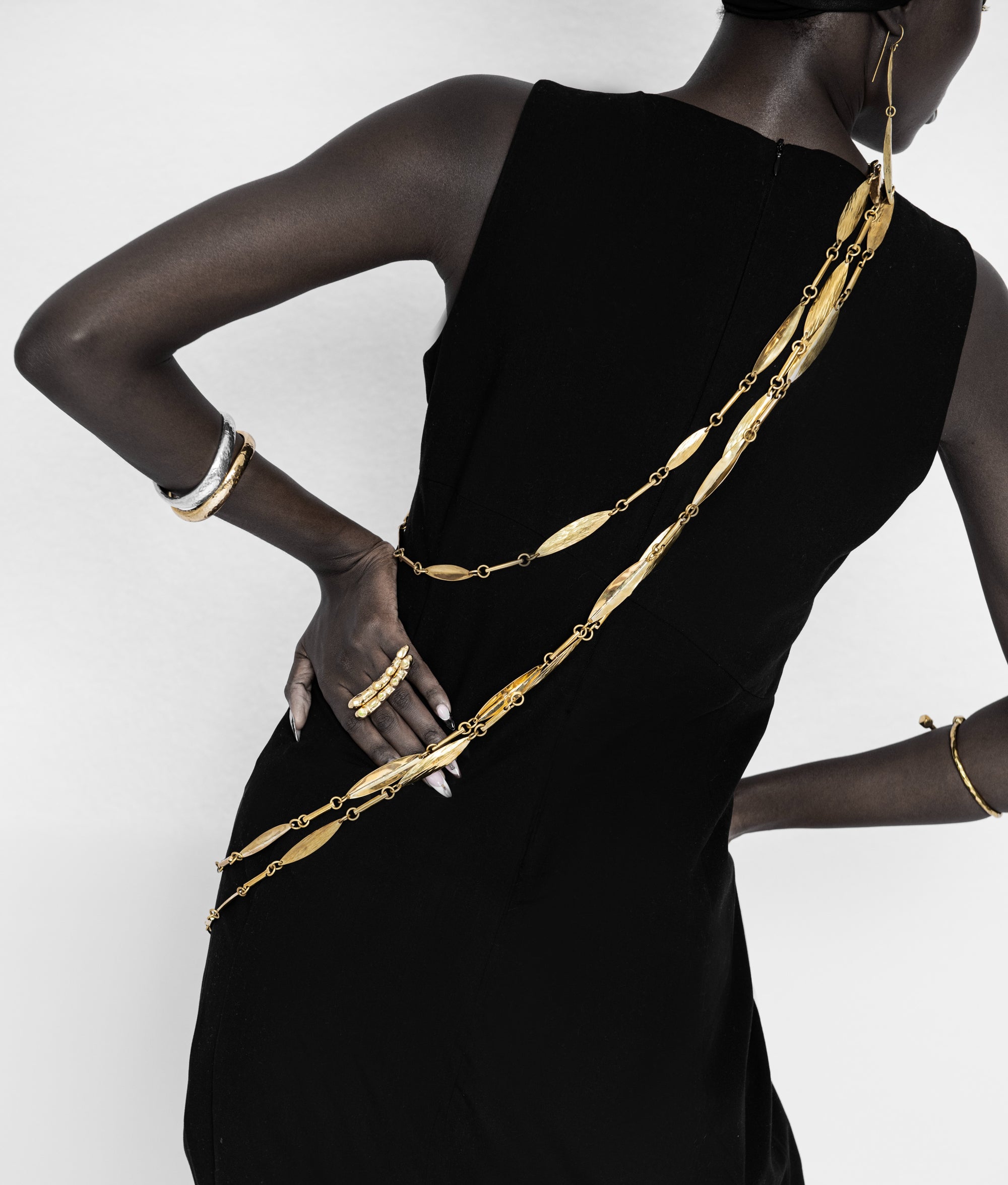 Adele Dejak Aminata Trio Set – a handcrafted trio of gold-tone brass necklaces featuring alternating hammered oval and sleek bar links, available in 88 cm, 127 cm, and 154 cm lengths, offering versatile styling options from bold layering to subtle elegance-model backside-view image