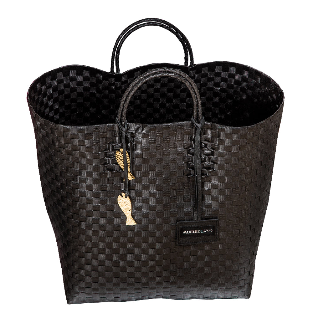 Handwoven black Theresa Bag by Adele Dejak, crafted from recycled plastic with a checkered pattern, featuring dual handles and adorned with signature brass charms, symbolizing sustainable African elegance-front view