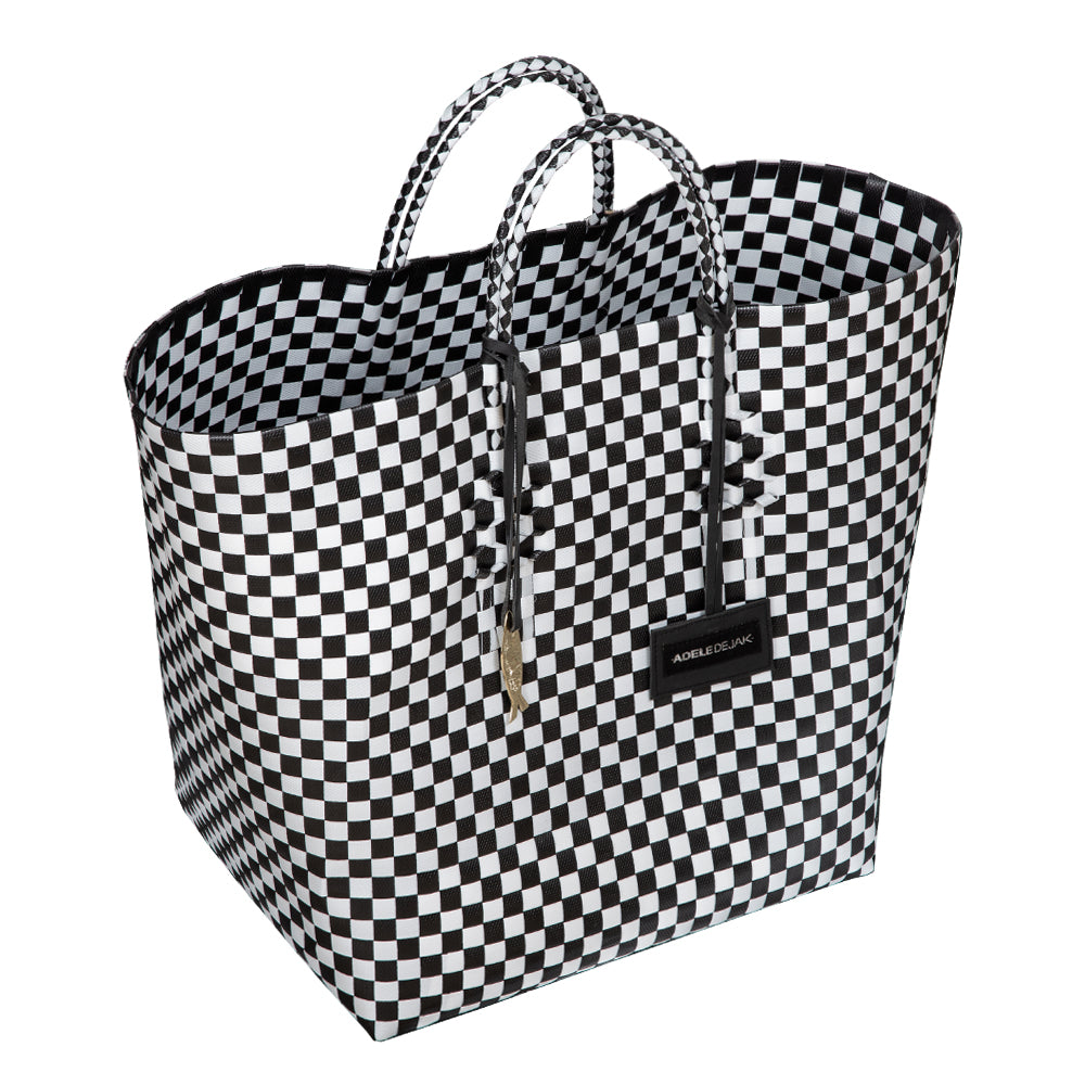 Handwoven black Theresa Bag by Adele Dejak, crafted from recycled plastic with a checkered pattern, featuring dual handles and adorned with signature brass charms, symbolizing sustainable African elegance-up close view